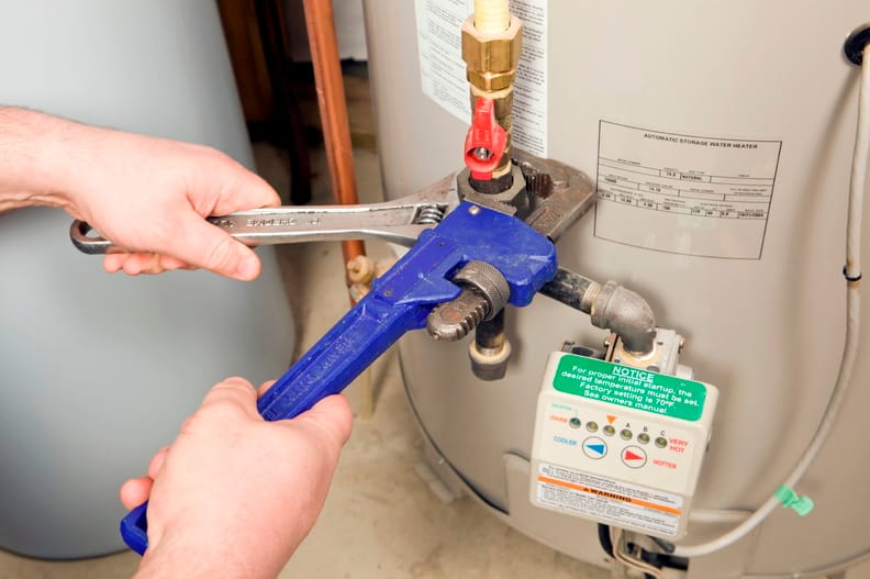 Plumber repairing water heater pipe connection in Monterey, California home