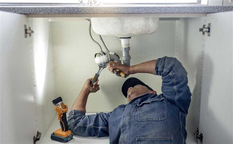 Plumber repairing kitchen sink drain pipes in Monterey, California